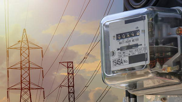 Electric power lines in the background with an electric utility meter in the foreground.