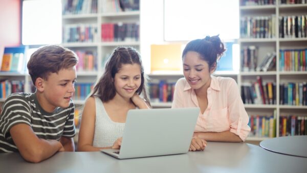 Three children looking at a laptop in a library