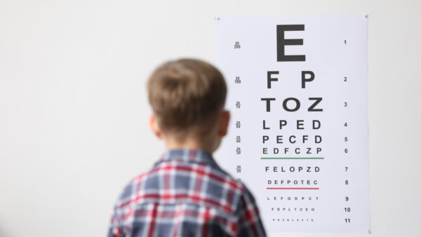 Eyesight examination. Little boy looking at vision test chart indoors, back view