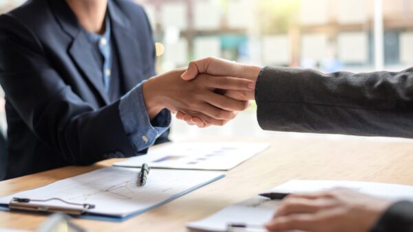 Business people shaking hands at a meeting with papers on the table.