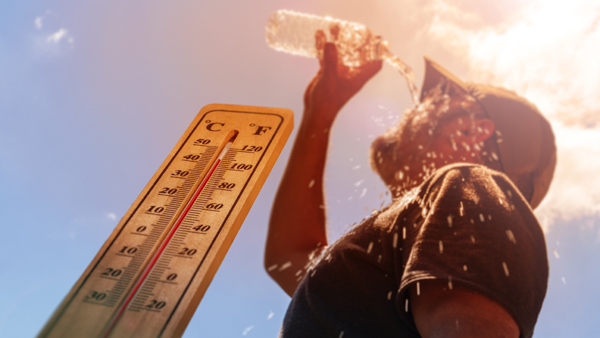 Thermometer reading 100 degrees Fahrenheit next to man pouring water on his face.