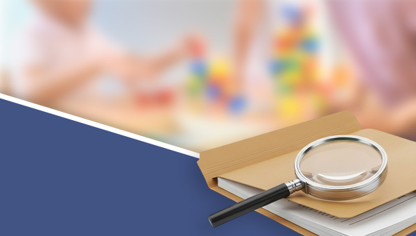 Magnifying glass sitting on folder full of documents with childcare activity in background