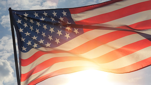 Close up American flag waving in the wind against sunset.