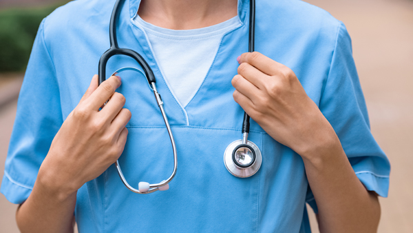 Female nurse in blue scrubs with stethoscope around neck.