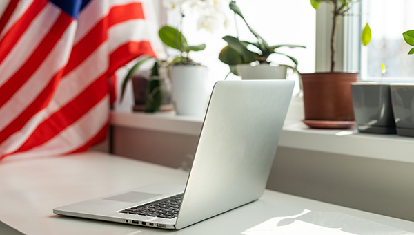 US flag and laptop on white background with potted plants
