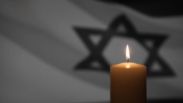 Burning candle on Israel flag background. International Holocaust Remembrance Day, January 27.