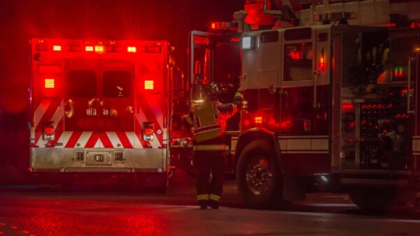firetruck and ambulance on a wet road with red lights.