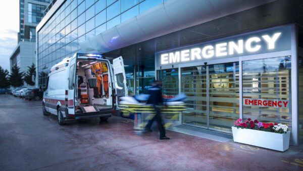 ambulance sitting in front of an emergency room door as an emt unloads a patient.