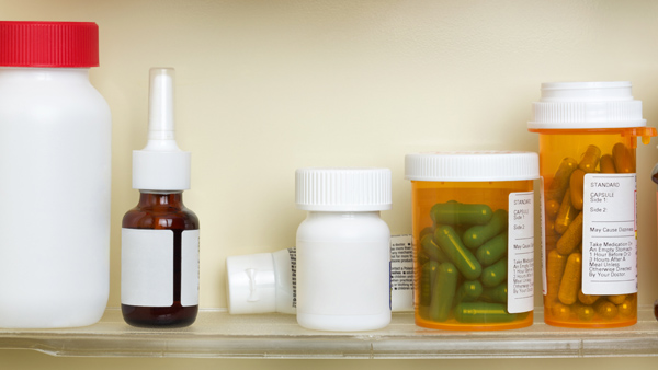 Open medicine cabinet, with shelf featuring over the counter medicine and prescription drug containers.