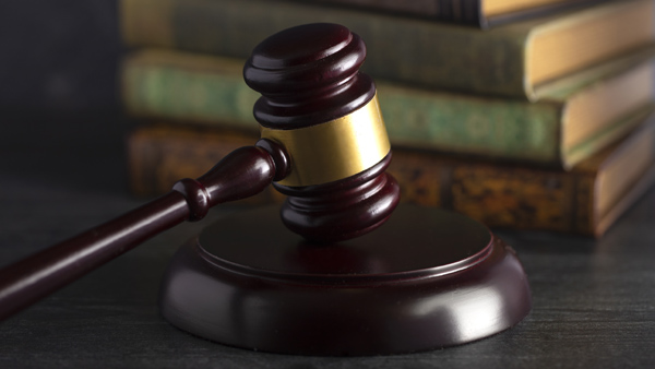 Judge’s gavel on desk with law books in background