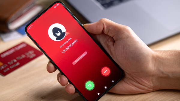 Cellphone in right hand with screen reading “unknown incoming call.”