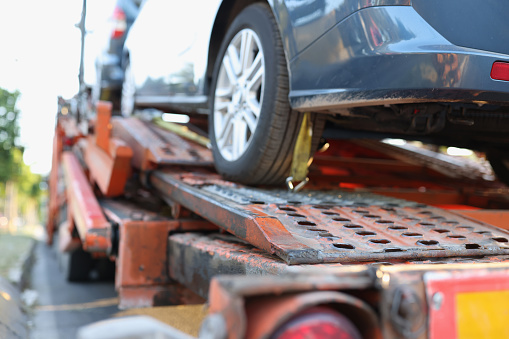 A dark car on the bed of a tow truck.